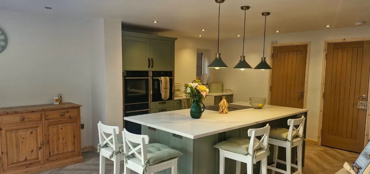 Kitchen with grey herringbone LVT flooring fitted around a sage green island